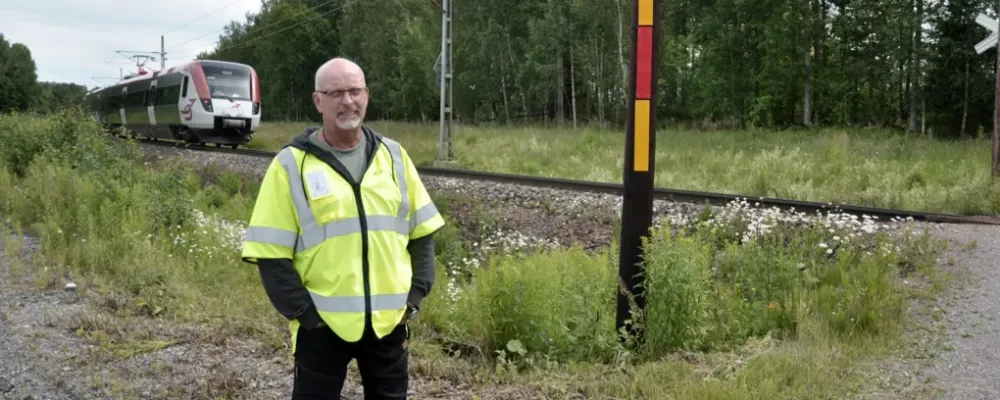 Projektledaren för arbetet med att bygga säkrare järnvägssträcka mellan Falun och Borlänge, Bengt Andersson står på platsen som om några veckor kommer att ha en ny rörbro installerad.
I bakgrunden glittrar mellan tallgrenarna sjön Runn. Fritidsstugorna ligger som ett pärlband efter varandra längs med strandkanten. Foto: Stefan Bratt