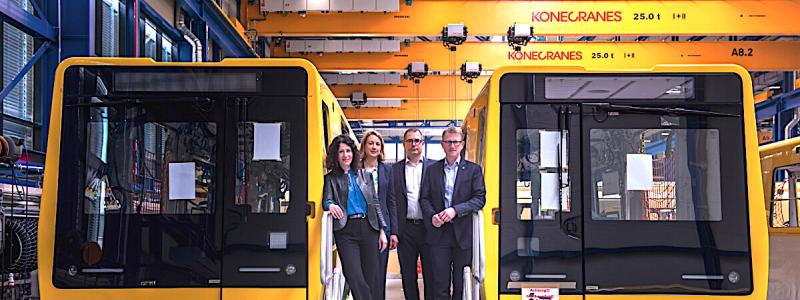 Berlins mobilitetssenator Bettina Jarasch fick vid ett platsbesök en första inblick i den nya tunnelbanan. I Stadlers monteringshall i Pankow sydväst om Berlin står för närvarande tolv gula vagnar av den nya tunnelbaneserien tätt uppställda. Totalt byggs åtta testtåg i inledningsskedet, där varje tåg består av flera vagnar. Fyra av tågen är avsedda för smalprofil och fyra för storprofil. Produktionen har inletts med smalprofilstågen, som används på linjerna U1 till U4.Vid en pressvisning av den nya generationen tunnelbanetåg. Bild: Team On.