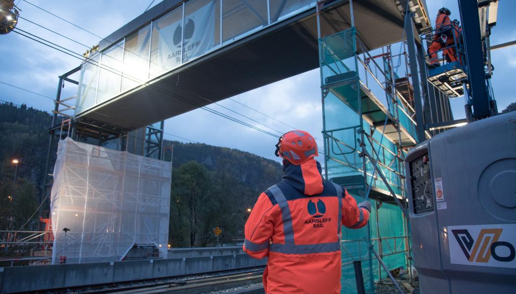 Aarsleff Rail lyfter en gångbro på plats på Evanger Station. Brokonstruktioner och hisstorn har byggts i Danmark och transporterats med lastbil till Norge.