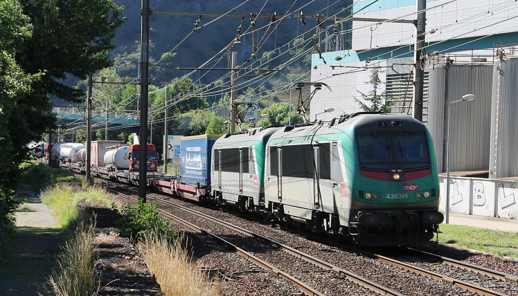 Här ett lokaltåg, men från och med 1 april är även italienska Trenitalias snabbtåg Frecciarossa tillbaka på sträckan, med två dagliga tur- och returresor. Det markerar slutet på en långvarig avstängning som inte bara drabbade järnvägen, utan också påverkade motorvägen A43 och landsvägen RD1006. Bilden visar två ledande lok av typen SNCF BB 36300 drar ett Modalohr-tåg på väg mot Italien vid Saint-Michel-de-Maurienne, längs sträckan Aiton–Orbassano. Foto: Wikipedia Common, kredit: Mouliric / Eget verk. 