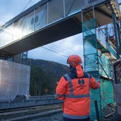 Aarsleff Rail lyfter en gångbro på plats på Evanger Station. Brokonstruktioner och hisstorn har byggts i Danmark och transporterats med lastbil till Norge.