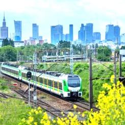 FLIRT-tåg från Stadler på väg i Warszawas omgivningar. I bakgrunden syns den polska huvudstaden skyline. Foto: Stadler